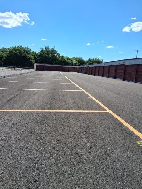 Wide striped outdoor parking spaces for vehicles, trailers, and RVs at Canutillo Self Storage.
