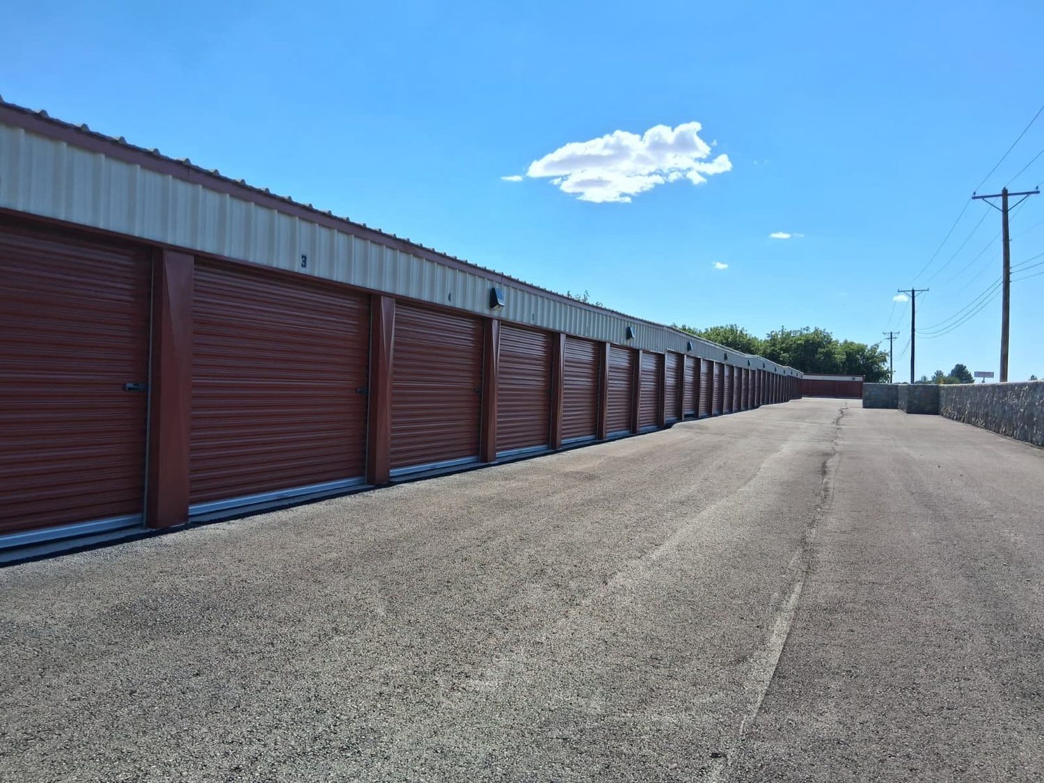 A long continuous row of red-door drive-up units stretching down a paved lane at Canutillo Self Storage.